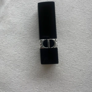 Rouge Dior läppstift 520 Feel Good - Rouge Dior läppstift i nyansen 520 Feel Good. Snygg, klassisk hylsa i svart med silverdetaljer och CD-logga. Läppstiftet har en satin-finish och en intensiv rosa färg. Perfekt för dig som vill ha en lyxig känsla i sminkväskan. Kommer utan förpackning, oanvänd och otestad, om du köper fler av dessa läppstift kan jag tänka mig bättre pris. Rensning inför flytt. Vissa märken på själva skalet på läppstiftet kan förekomma då jag förvarat alla i samma låda 