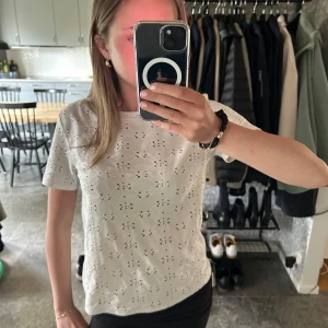 Vit topp - Säljer en söt vit t-shirt som är perfekt till sommaren och enkel att matcha med både jeans och kjol. Blusen har en rak passform och är tillverkad i ett lätt material.