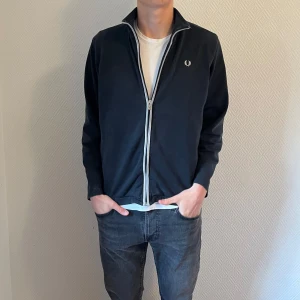 Marinblå zip från Fred Perry - Säljer denna feta marinblåa Fred Perry zip. Skick 9/10. Endast 299kr, perfekt nu för sommaren. Vänligen skriv till mig ifall det finns frågor.