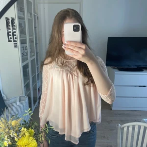 Ljusrosa blus med spetsdetaljer  - Supersöt ljusrosa blus med spets upptill och på ärmarna. Blusen har en lös passform och trekvartsärmar. Perfekt för dig som gillar romantisk och feminin stil. Tunt och luftigt material.