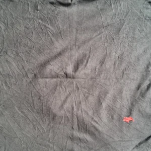 Svart t-shirt från Polo Ralph Lauren - Svart t-shirt från Polo Ralph Lauren med liten röd broderad logga nertill. Klassisk passform och tillverkad i mjuk bomull. Perfekt för en stilren och enkel look.