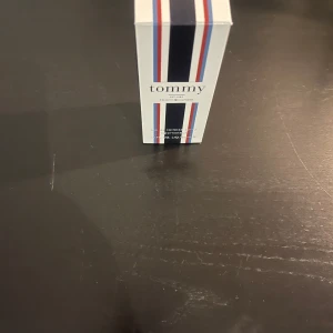 Tommy Hilfiger herrparfym - Fräsch herrparfym från Tommy Hilfiger i en stilren, transparent glasflaska med silverfärgad spray och lock. Förpackningen har klassiska ränder i rött, vitt och blått samt loggan 'tommy' på framsidan.