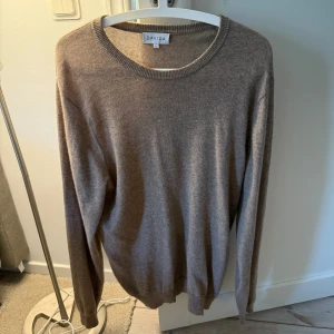 Beige kashmirtröja från Davida - Mjuk och lyxig beige kashmirtröja från Davida. Klassisk rund halsringning och långa ärmar. Perfekt för lager-på-lager och passar till det mesta i garderoben.