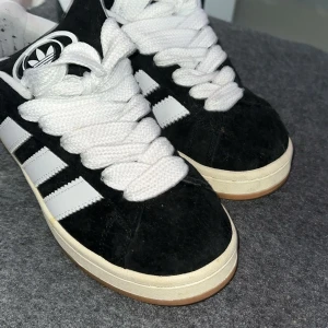 Svarta Adidas Campus sneakers med vita ränder - Säljer ett par klassiska Adidas Campus sneakers i svart mocka med vita ränder och vit sula. Skorna har grova vita snören och gummisula i brunt. Använt Max 2 gånger. Kan tänkas gå ner i pris 