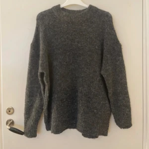Mörkgrå stickad tröja - Mysig mörkgrå stickad tröja med rund hals och lång ärm. Tröjan har en lite lös passform och är perfekt för kyligare dagar. Passar både till jeans och mjukisbyxor.