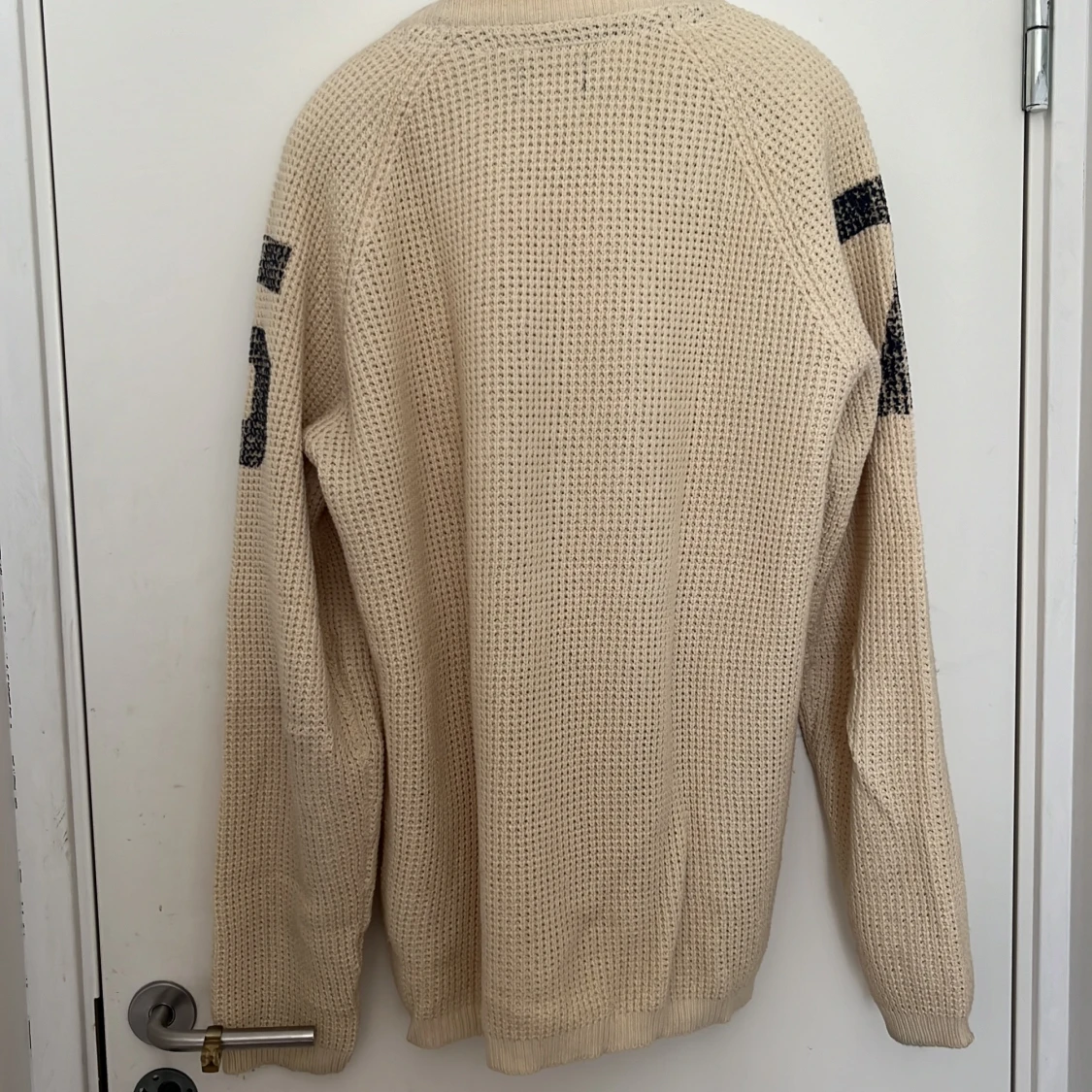 Beige stickad tröja med svarta siffror på ärmarna - 1