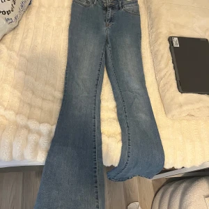 Blå bootcut jeans från Vila - Säljer ett par blå bootcut jeans från Vila i storlek XS. Jeansen har klassisk femficksdesign, dragkedja och knapp framtill samt snyggt utsvängda ben.