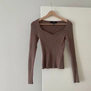 Brun ribbad topp från Vero Moda - Säljer en brun ribbad långärmad topp från Vero Moda. Tröjan har en snygg sweetheart-urringning och sitter figurnära.
