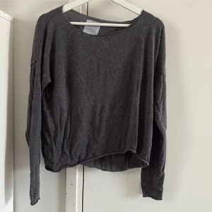Mörkgrå långärmad tröja från Angelology - Mysig mörkgrå tröja från Angelology med rund halsringning och långa ärmar. Tröjan har en något lös passform och är tillverkad i ett mjukt material som passar perfekt till vardags.