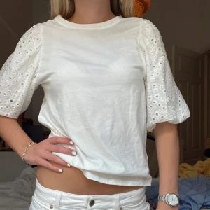 Vit blus med broderade puffärmar - Säljer en vit blus med korta puffärmar i broderad bomull. Ärmarna har fina hålbroderier och ger en romantisk känsla. Perfekt till sommaren och passar till både jeans och kjol.