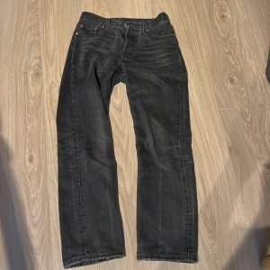 Levis 501, 90s w25 L30 - Säljer ett par svarta Levi's jeans med klassisk femficksdesign och raka ben. Byxorna har  en brun patch bak i midjan. Perfekta för dig som gillar en tidlös och enkel stil.