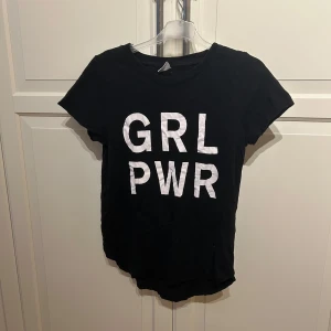 Svart t-shirt med GRL PWR-tryck från Gina Tricot - Cool svart t-shirt från Gina Tricot med stort vitt GRL PWR-tryck på framsidan. Klassisk rund halsringning och korta ärmar. I strl S