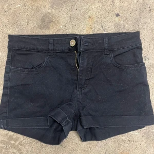 Svarta jeansshorts med uppvik - Svarta jeansshorts med klassisk femficksdesign och uppvikta benslut. Stängs med knapp och dragkedja framtill. Perfekta för varma dagar och enkel att matcha med olika toppar. De är från H&M och i storleken runt 146. Skriv till mig för extra fråga eller vidare oklarhet.🧡