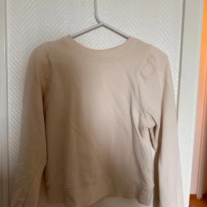 Beige långärmad tröja från KappAhl - Säljer en enkel och stilren beige långärmad tröja från KappAhl i storlek XS. Tröjan har rund halsringning och är tillverkad i mjukt bomullsmaterial. Perfekt för en avslappnad och snygg look.