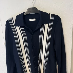 Skjorta från Sandro Paris - Mörkblå och vitrandig skjorta från Sandro. Helt oanvänd. 