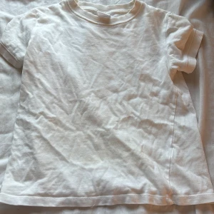 Vit basic t-shirt i bomull från Zara - Enkel vit t-shirt i mjuk bomull med rund hals och korta ärmar. Klassisk passform och ribbade muddar vid hals och ärmslut. Perfekt till jeans eller shorts för en clean look.