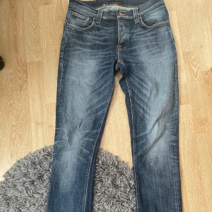 Nudie Jeans grim Tim - Tjena! Säljer nu ett par snygga och välvårdade jeans från Nudie Jeans i modellen grim Tim. I storlekarna: W31 L34. Med färgen blå denim med snygg slitning och detaljer i orange sömmar. Jensen är tillverkad i 100% bomull, vilket gör dem både är sköna och hållbara. Använda men i fint skick inga stora fläckar, bara naturligt snyggt slitage som hör till stilen. Hör gärna av dig vid frågor eller för fler bilder! Nypris ca 1 400 kr. Mitt pris: 449kr kom gärna med bud!
