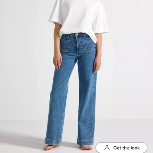Blå wide jeans från Lindex, strl 36 - Säljer ett par blå jeans från Lindex i modellen wide. De har hög midja, raka vida ben och stora fyrkantiga fickor fram. 
