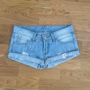 ljusblåa jeansshorts  - supersnygga lågmidjade vintage ljusblåa jeanshorts med revor. storlek 36. Midja: 38 cm, höjd: 19