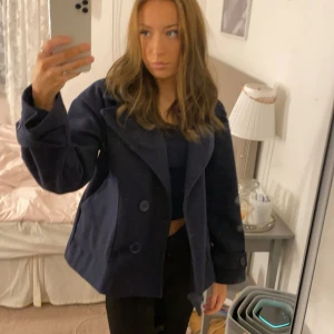 Mörkblå kappa med stora knappar - Säljer en mörkblå rock med bred krage och stora knappar framtill. Jackan har en loose passform och långa ärmar, perfekt för dig som gillar en chill och stilren look. Passar till många outfits och är enkel att matcha.