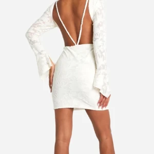 Vit spetsklänning med öppen rygg - Superfin vit kortklänning med spetsdetaljer och långärmade trumpetärmar. Klänningen har en öppen rygg och figurnära passform. Använd en gång på min student så i fint skick!💕