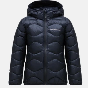 Svart dunjacka från Peak Performance - Snygg svart dunjacka från Peak Performance med vågformat quiltat mönster. Jackan har huva, dragkedja framtill och diskret logga på bröstet. Perfekt för kalla dagar och riktigt skön att bära.