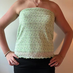 Grön blommig tubtopp från Primark - Söt grön tubtopp från Primark med små blommor i lila och rosa. Toppen har bandeau-modell och vågig kant nertill som ger en extra detalj. Perfekt för varma dagar och enkel att matcha med jeans, shorts eller kjol. Andvänds lika gärna som kjol till en annan överdel.