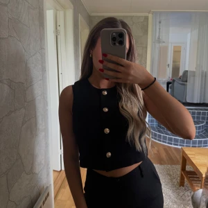 Svart croppad väst med guldknappar H&M - Svart croppad väst från H&M med fyra snygga guldknappar framtill. Helt ny och oanvänd!