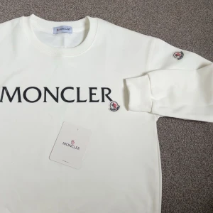 Vit Moncler sweatshirt med logga - Snygg vit sweatshirt från Moncler med stor svart logo text och en moncler patch på mode magen och armen. Extremt fet! Storlek Xs-S