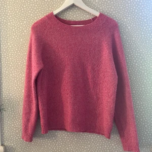 Rosa stickad tröja från Vero Moda - Superfin rosa stickad tröja från Vero Moda i storlek S. Tröjan har en klassisk rund halsringning, ribbade muddar och lång ärm. Perfekt för dig som vill ha en mysig och färgglad look till hösten eller vintern. Är ganska nopprig men ändå i fint skick