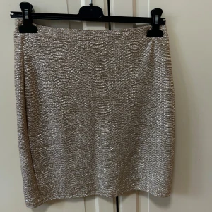 Glittrig guld minikjol - Supersnygg glittrig guld kjol från H&M i rak modell. Perfekt för en utekväll, den kan man ha lågmidjad mid och högmidjad