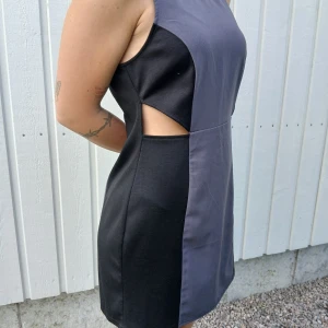 Klänning med rolig detalj  - Snygg klänning med öppet i sidorna så att man ser midjan. Det står 42, men den är en medium.