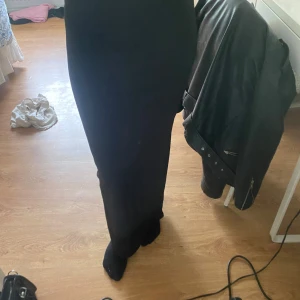 Svart vid kjol med slits - Säljer en svart kjol med vid passform och snygg slits nertill på benen. Kjolen har låg midja och är perfekta om du gillar en loose och chill stil. Materialet känns mjukt och stretchigt, superbekväma att ha på sig hela dagen.