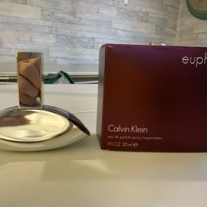 Calvin Klein Euphoria parfym 30ml - Calvin Klein Euphoria eau de parfum 30ml med elegant, futuristisk flaska i silverfärgat glas och lila toner. Kommer i en snygg mörklila kartong. Doften är sensuell och modern, perfekt för dig som gillar lyxiga och djupa parfymer. Endast tagit några droppar från flaskan.