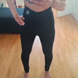 Svarta fleecefodrade leggings - Svarta leggings från Mian Xiao Mei med hög midja och mjukt fleecefoder på insidan. Perfekta för kalla dagar när du vill ha både värme och stil. Stretchigt material som sitter tight och bekvämt. Diskret logga framtill vid midjan. Jag har 2 par tights som är likadana, det blir 200 kr om du vill ha båda 