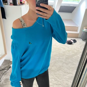 Over size blå stickad tröja från Skill - Snygg blå stickad tröja från Skill med v-ringning och liten broderad fågel på bröstet. Tröjan har lång ärm och en loose passform som ger en chill vibe. Perfekt att slänga på sig över ett linne eller t-shirt för en avslappnad look.