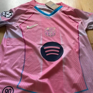 Barcelona Lamine Yamal rosa matchtröja - Snygg Barcelona fotbollströja i rosa och lila toner från Nike, med Lamine Yamal och nummer 10 på ryggen. Tröjan har korta ärmar, klubbmärke och Nike-logga på bröstet samt Spotify-logga framtill. Tillverkad i lätt och ventilerande material, perfekt för match eller träning.