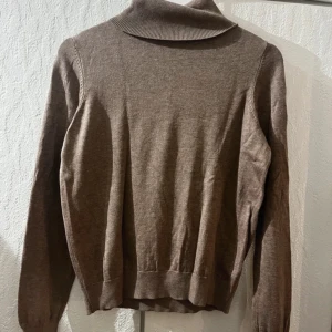 Brun polotröja från H&M - Snygg brun polotröja från H&M i mjuk och tunn stickad bomullsmix. Tröjan har lång ärm, ribbade muddar och klassisk polokrage. Perfekt för lager-på-lager och enkel att matcha med jeans eller kjol.