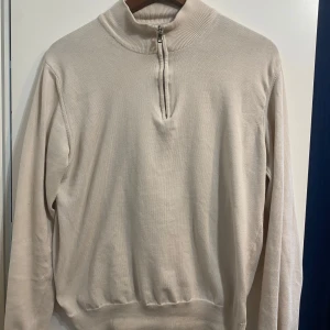 Beige tröja från Oscar Jacobson - Säljer en stilren beige tröja från Oscar Jacobson med dragkedja vid halsen. Tröjan har långa ärmar och är tillverkad i Italien. Perfekt för en elegant och avslappnad look. Storlek S. Tror original priset är 1500kr