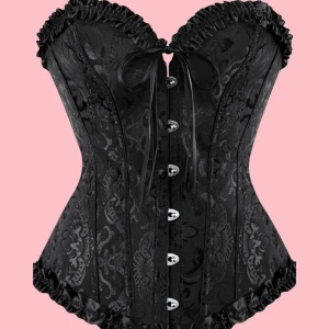 Svart korsett med spetsdetaljer - Elegant svart korsett med vackra spetsdetaljer och knappar framtill. Den har en dekorativ rosett och volangkant som ger en lyxig känsla. Perfekt för att skapa en stilfull look. använd 1 gång