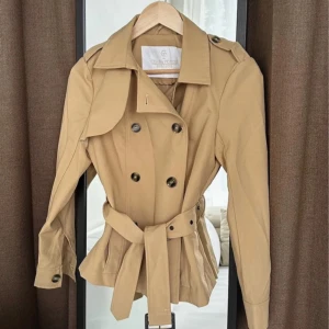 Beige kort trenchcoat  - Snygg beige trenchcoat från Chiara Forthi med klassisk design. Använd två gånger och Perfekt för vår och höst!