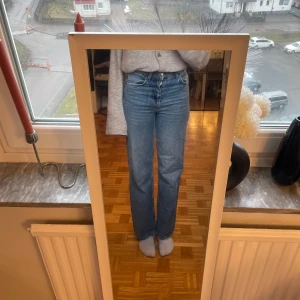 Blå jeans med hög midja - Snygga blå jeans med hög midja och rak passform. Perfekta för en avslappnad stil. Klassisk design med fem fickor och knappgylf. 