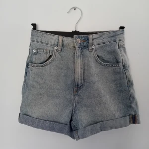 Blå jeansshorts från H&M - Snygga blå jeansshorts med hög midja och klassisk femficksdesign. De har en uppvikt kant och stängs med knapp och dragkedja. Perfekta för en avslappnad stil. Säljer de då de inte passar längre. 