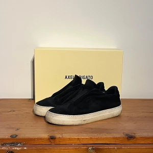 Axel Arigato 360 laceless - Snygga svarta sneakers från Axel Arigato i mocka. Modellen heter 360 laceless. Okej skick men kan behöva en ordentlig tvätt. Vänligen hör av dig vid frågor eller funderingar! 