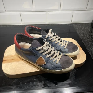 Philippe model skor - Snygga sneakers i blått med bruna detaljer och vita sulor. Skorna har snörning och en unik brun detalj på sidan. Perfekta för en avslappnad stil. 7/10 skick, priset är ej hugget i sten ⭐️⭐️⭐️