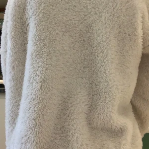 Vit fluffig hoodie - Mysig vit hoodie i fluffigt material med stor huva. Perfekt för kalla dagar när du vill känna dig extra bekväm och varm.