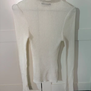 Vit ribbad tröja från Gina Tricot - Säljer en stilren vit ribbad tröja från Gina Tricot. Tröjan har en tight passform och långa ärmar, den är genomskinlig och lite skimrig i materialet