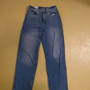 Blå 90-tals Baggy Jeans från H&M - Säljer ett par coola blå baggy jeans från H&M:s Recycled Denim Collection. Dessa jeans har en avslappnad passform med hög midja och klassisk femficksdesign. Perfekta för en retro look!