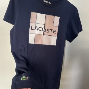 Lacoste T-shirt - Säljer en snygg mörkblå  t-shirt som e perfekt nu för sommaren, Den är i storlek S och är använd ett fåtal gånger. Hör av er om ni har frågor!