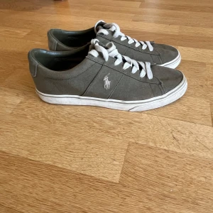  sneakers från Polo Ralph Lauren - Snygga mörkgröna sneakers från Polo Ralph Lauren med vit sula och klassisk snörning. Skorna har en stilren design med Polo-loggan på sidan. Perfekta för en avslappnad stil.